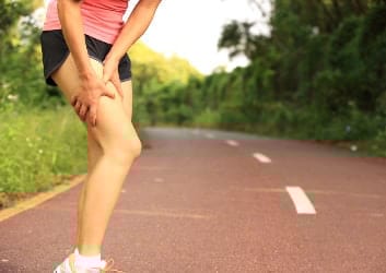 Übersäuerte Sportlerin hält sich den Oberschenkel
