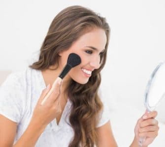 Frau schminkt sich mit Puder