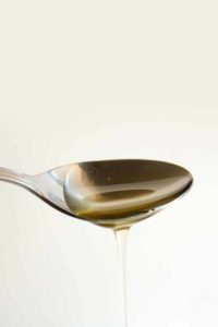 heruntertropfender Agavendicksaft auf einem Metalllöffel