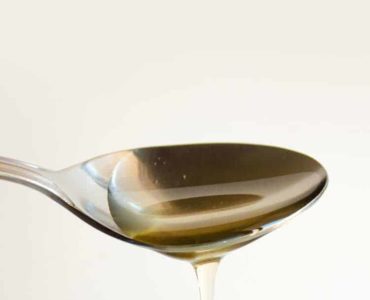 heruntertropfender Agavendicksaft auf einem Metalllöffel