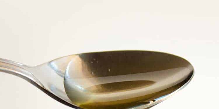 agavendicksaft heruntertropfender Agavendicksaft auf einem Metalllöffel