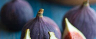Aufgeschnittene und ganze Feigen auf blauem Tisch