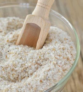 Weiße Flohsamenschalen im Glas mit Holzschäufelchen