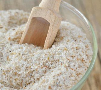 Weiße Flohsamenschalen im Glas mit Holzschäufelchen