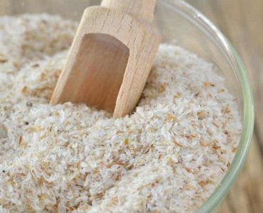 Weiße Flohsamenschalen im Glas mit Holzschäufelchen