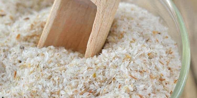 Weiße Flohsamenschalen im Glas mit Holzschäufelchen