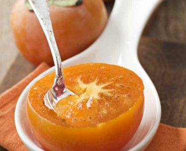 Halbierte orangefarbige Kaki mit Löffel