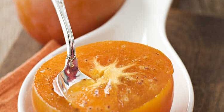 kaki Halbierte orangefarbige Kaki mit Löffel