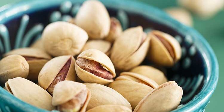 Pistazien mit Schale in türkiser Keramikschüssel