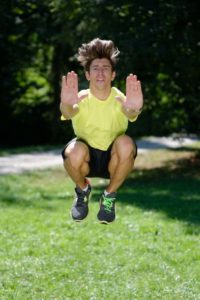 Mann macht Tuck Jumps im Park