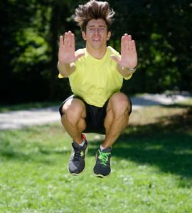 Mann macht Tuck Jumps im Park