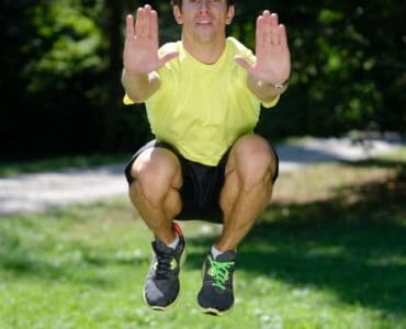 Mann macht Tuck Jumps im Park