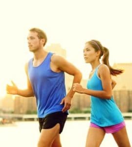 Junger Mann und junge Frau mit blauen T-Shirts joggen nebeneinander mit optimalem Trainingspuls