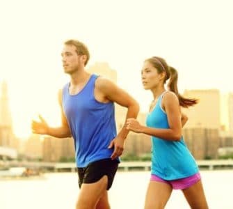 Junger Mann und junge Frau mit blauen T-Shirts joggen nebeneinander mit optimalem Trainingspuls