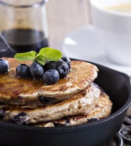 Pancakes in einer schwarzen Pfanne mit Blaubeeren garniert