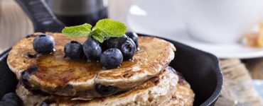 Pancakes in einer schwarzen Pfanne mit Blaubeeren garniert