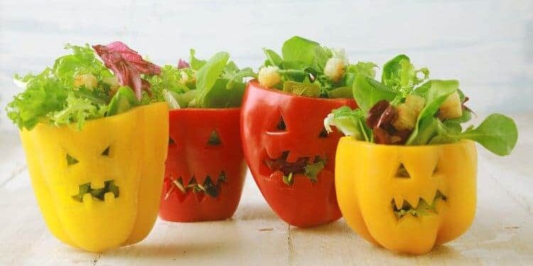 grusel-paprika-mit-salat Gelbe und rote Paprikas, die mit gruseligen Fratzen verziert wurden