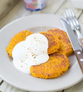 Drei Möhren-Couscous-Bratlinge mit Quark auf weißem Teller serviert