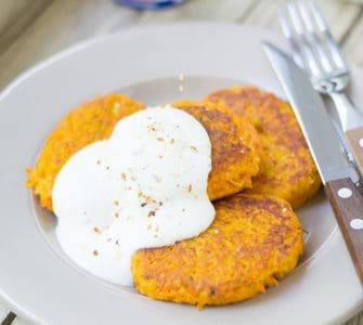 Drei Möhren-Couscous-Bratlinge mit Quark auf weißem Teller serviert