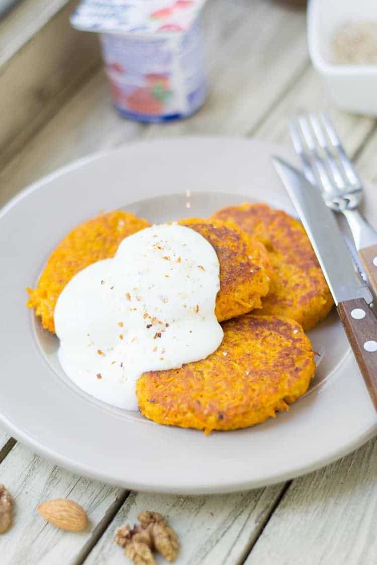 Drei Möhren-Couscous-Bratlinge mit Quark auf weißem Teller serviert