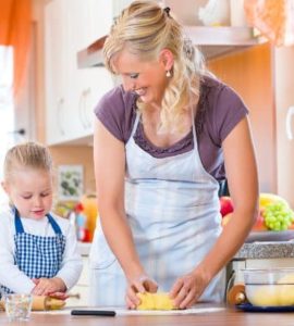Mutter und Kind mit Schürze backen Plätzchen