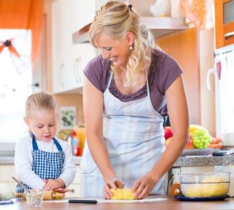 Mutter und Kind mit Schürze backen Plätzchen