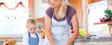 Mutter und Kind mit Schürze backen Plätzchen