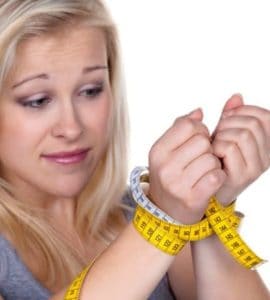 Blonde Frau mit Maßband als Fessel um die Handgelenke gewickelt