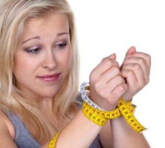 Blonde Frau mit Maßband als Fessel um die Handgelenke gewickelt