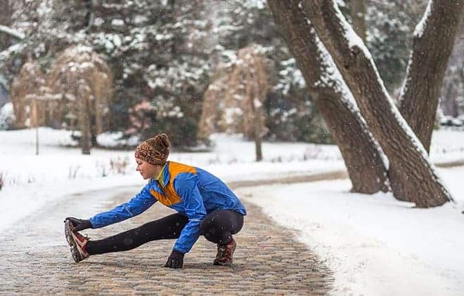 Frau im Schnee dehnt sich.