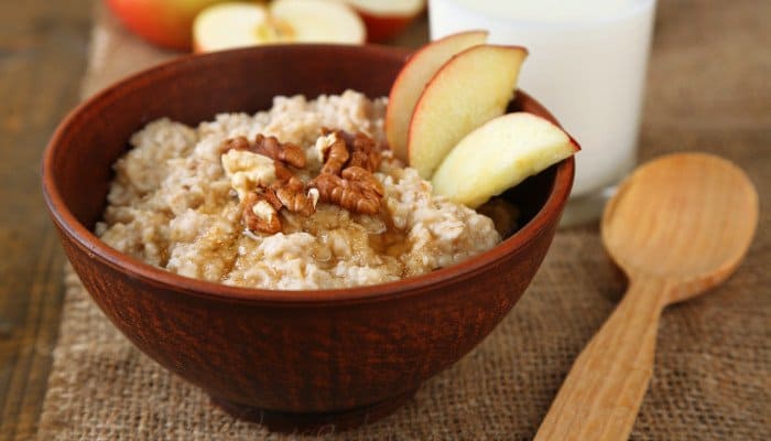 Holzschüssel mit Haferbrei, garniert mit Apfelscheiben