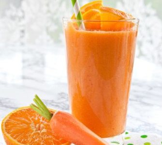 1 Glas A-C-E-Smoothie mit Strohhalm. Davor eine halbe Orange und eine Karotte