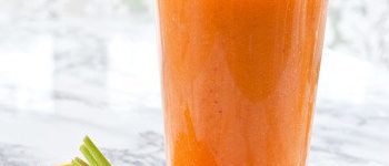 1 Glas A-C-E-Smoothie mit Strohhalm. Davor eine halbe Orange und eine Karotte