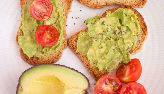 Brotscheiben belegt mit grüner Avocado und Tomaten