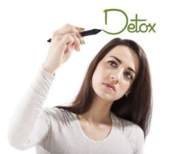 Junge Frau, die das Wort Detox auf eine virtuelle Glasscheibe schreibt