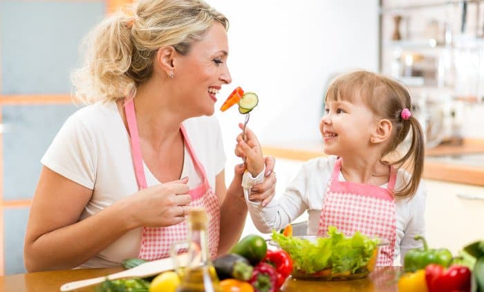Mama und Kind beim Essen von gesundem Gemüse