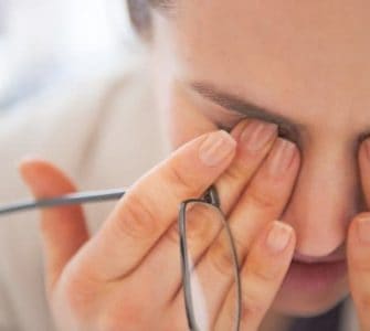 Im Büro arbeitende Frau, die sich vor Müdigkeit die Augen reibt