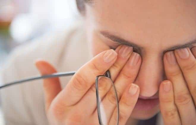 Im Büro arbeitende Frau, die sich vor Müdigkeit die Augen reibt