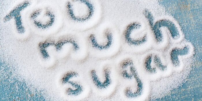 zu-viel-zucker Die Worte Too much sugar geschrieben in eine Fläche ausgestreuten Zuckers