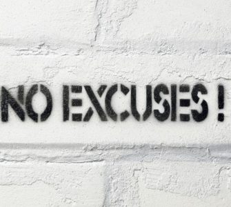 No Excuses Schriftzug auf weißer Backsteinwand.