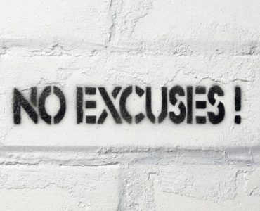No Excuses Schriftzug auf weißer Backsteinwand.