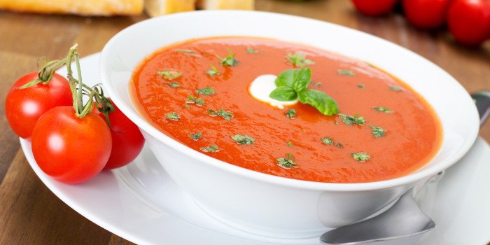 Schüssel Tomatensuppe dekoriert mit grünen Blättern