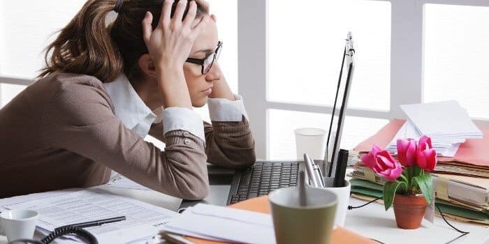 Frau vorm Laptop ist gestresst und fasst sich an den Kopf