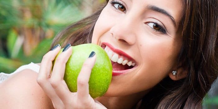 Frau beisst in Apfel Frau beisst in grünen Apfel