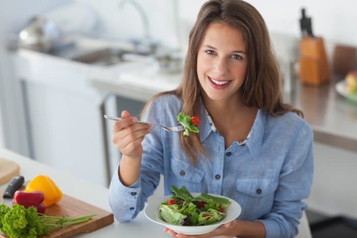 Frau in blauem Jeanshemd isst Salat