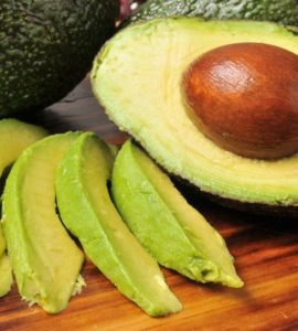 Avocados als ganze Frucht, halbiert und in Streifen geschnitten