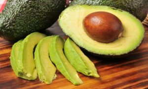 Avocados als ganze Frucht, halbiert und in Streifen geschnitten