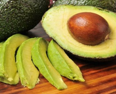 Avocados als ganze Frucht, halbiert und in Streifen geschnitten