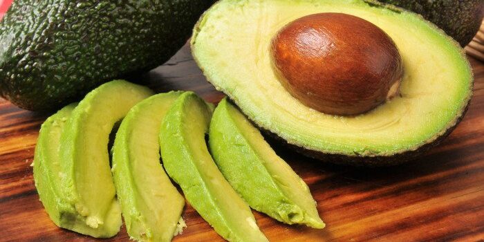 Avocados als ganze Frucht, halbiert und in Streifen geschnitten