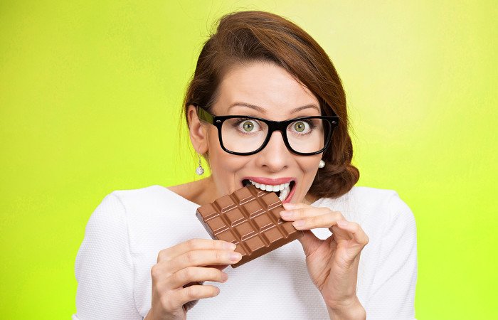 Frau beißt in eine Tafel Schokolade